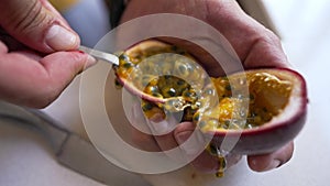 Unrecognizable man eating passion fruit with spoon indoors. High angle view male hand with organic vitamin healthful