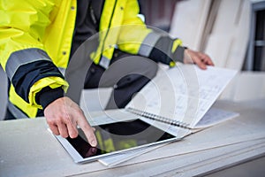 Unrecognizable man engineer on construction site, holding tablet with blueprints.