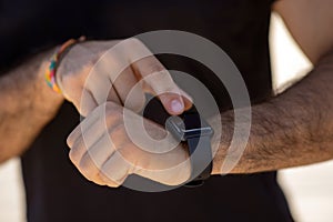 Unrecognizable man in fitwear uses smartwatch for workout monitoring outdoors