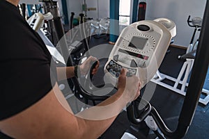 Unrecognizable man hands on elliptical trainer handrails in sport club. Cardio workout background, running on treadmill. Healthy