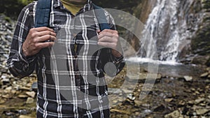 Unrecognizable Man Hands Holds A Backpack Strap On Waterfall Background Hiking Journey Travel Trek Concept