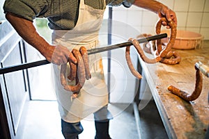 Unrecognizable man hanging homemade raw sausages on wooden stick