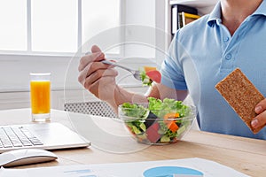 Unrecognizable man has healthy business lunch in modern office i