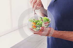 Unrecognizable man has healthy lunch, eating diet vegetable salad