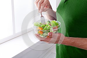 Unrecognizable man has healthy lunch, eating diet vegetable salad