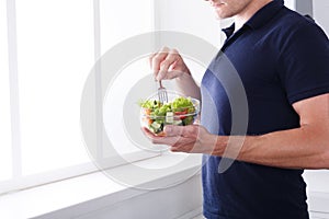 Unrecognizable man has healthy lunch, eating diet vegetable salad