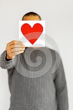 Unrecognizable man hold Valentine Copy space card. Happy Valentine's Day. Anonymous person is hiding face under greeting card in 