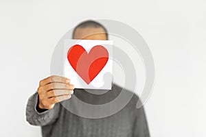 Unrecognizable man hold Valentine Copy space card. Happy Valentine's Day. Anonymous person is hiding face under greeting card in 