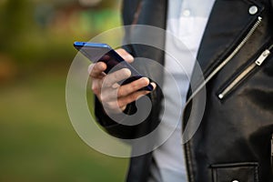 Unrecognizable man holding mobile phone in hand, blurred background
