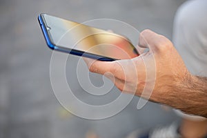 Unrecognizable man holding mobile phone in hand, blurred background