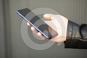 Unrecognizable man holding mobile phone in hand, blurred background