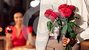 Unrecognizable Man Holding Roses Having Date With Girfriend In Restaurant