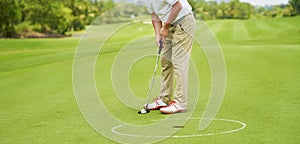 Unrecognizable man playing golf putting on green