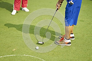 Unrecognizable man playing golf putting on green
