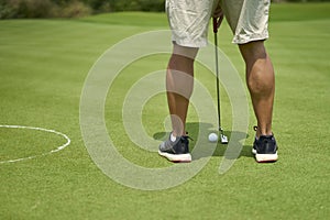 Unrecognizable man playing golf putting on green