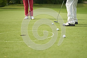 Unrecognizable man playing golf putting on green