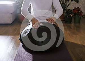 Unrecognizable man playing on hang sitting on yoga mat in yoga class. Sound healing concept