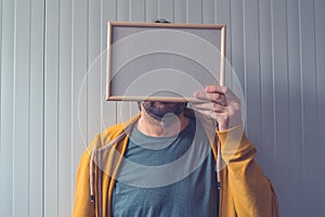 Unrecognizable man posing with blank picture frame over his face