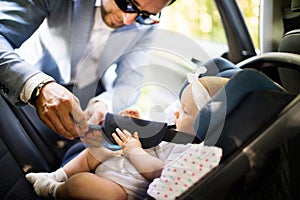 Unrecognizable man putting baby girl in the car.