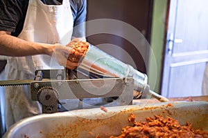 Unrecognizable man putting meat ball into sausage filler, close