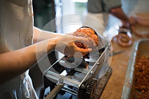 Unrecognizable man putting meat ball into sausage filler, close