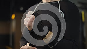 Unrecognizable man ready for fight at gym. Boxer wrapping hands in sport club