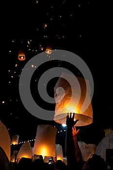 Unrecognizable man releasing paper lantern during Loi Krathong and Yi Peng festival in Chian Mai