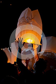 Unrecognizable man releasing paper lantern during Loi Krathong and Yi Peng festival in Chian Mai