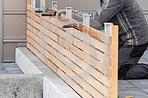 Unrecognizable man repairing new wooden fence near house