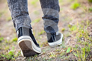 Unrecognizable man in rubber shoes stepping on footpath, rear view, closeup