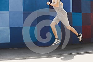 Unrecognizable man running against bright blue wall