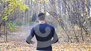 Unrecognizable man running along forest path. Male sportsman working out at nature. Strong and endurance athlete doing