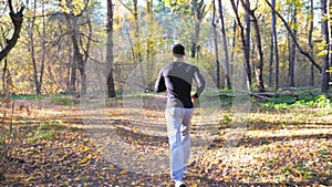 Unrecognizable man running along forest path. Male sportsman working out at nature. Strong and endurance athlete doing