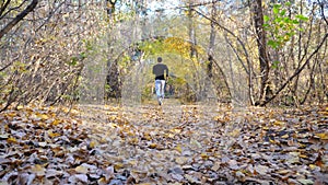 Unrecognizable man running fast along forest path. Strong and endurance athlete working out at nature. Sporty guy doing