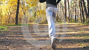 Unrecognizable man running fast along forest path at sunny day. Strong and endurance athlete working out at nature
