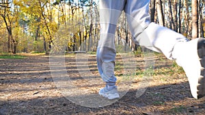 Unrecognizable man running fast along forest path at sunny day. Strong and endurance athlete working out at nature