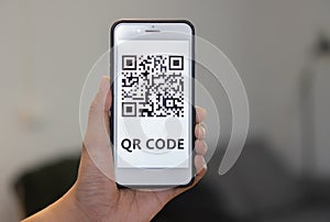 Unrecognizable man's hand holding modern smartphone with QR code on screen