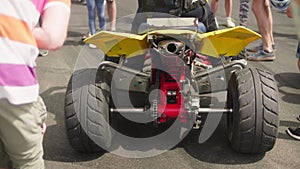 Unrecognizable man sitting on a parked ATV, close-up rear view