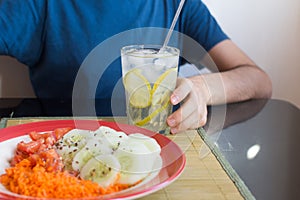Unrecognizable man sitting at table with glass of water and vegatable salad - healthy breakfast