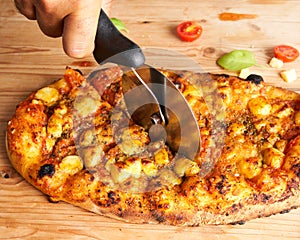 Unrecognizable man slicing an Italian pizza. Traditional food from Palermo, Sicily, Italy. Ingredients Tomato sauce, anchovy,