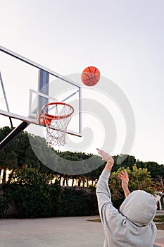 Unrecognizable man throwing a ball into a basket