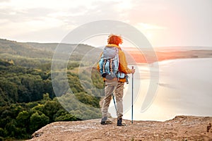 unrecognizable man trekking on mountains having relaxing break, holding hiking poles