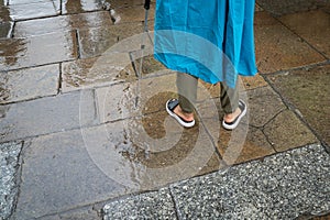 Unrecognizable man wearing a blue oilskin and sandal on a rainy day