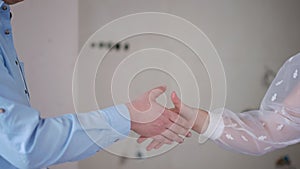 Unrecognizable man and woman passing key shaking hands standing in new apartment indoors. Young Caucasian seller and