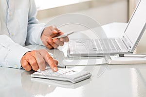 Unrecognizable man is working by using a Calculator and phone