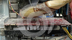 Unrecognizable master brushing a disassembled dusty computer with a brush, close-up