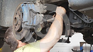 Unrecognizable mechanic repairing car with wrench tool at auto service. Professional repairman in uniform working