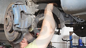 Unrecognizable mechanic repairing car with wrench tool at auto service. Professional repairman in uniform working