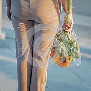 Unrecognizable middle aged woman, rear view with bouquet of sunflowers