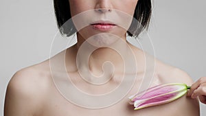 Unrecognizable Middle Aged Woman Stroking Neckline With Flower, Gray Background